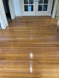 Freshly refinished bamboo plank flooring with a glossy Bona Traffic finish in front of white french doors