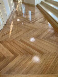 Close-up of herringbone bamboo floor pattern showing wood grain detail and glossy polyurethane finish near stairs