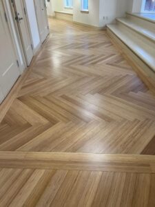 Herringbone pattern bamboo flooring with border inlay installed in a school entryway next to a built-in bench