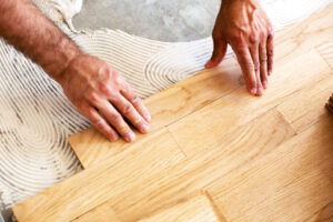 Installer fitting unfinished oak hardwood planks during installation, the step that follows proper acclimation