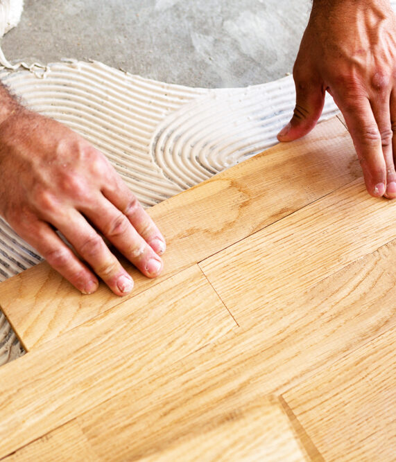 Installer fitting unfinished oak hardwood planks during installation, the step that follows proper acclimation